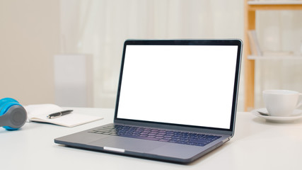 Fototapeta premium Mock up white screen laptop standing on the desk in the cozy living room at modern home.
