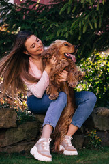 Beautiful young woman playing with her lovely dog  on yard outdo