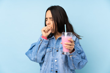 Young woman with strawberry milkshake over isolated blue background is suffering with cough and feeling bad