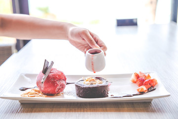 Close up the chocolate lava dessert with strawberry ice cream on white plate.