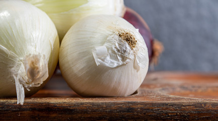 Onions (Allium cepa) in white, purple and yellow varieties on wooden surface