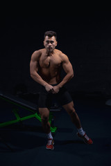 Fototapeta na wymiar male athlete shows body and muscles on dark wall background in gym, sexy guy bodybuilder, sports lifestyle, home sport.
