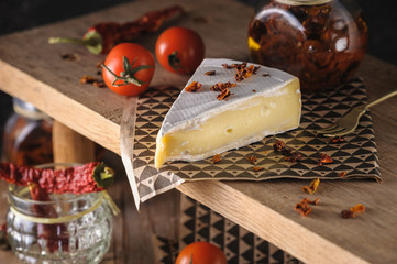 cream cheese brie beautiful serving on a wooden stand with cherry tomatoes and chili