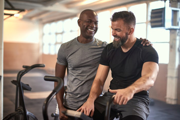 Two men laughing after exercising on stationary bikes