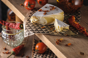 cream cheese brie beautiful serving on a wooden stand with cherry tomatoes and chili