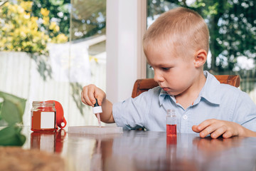 Little boy doing the experimental laboratory activity with colored water and pieces of glass....