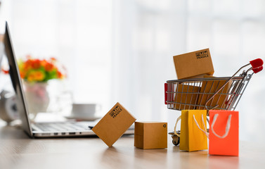 Online shopping concepts - Product package boxes in cart and laptop on desk with copy space