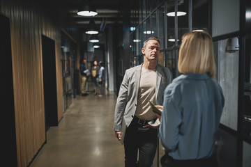 Mature businessman talking with a coworker in an office hallway