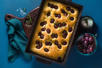 focaccia with red grapes on a blue table. Italian Cuisine, the perfect appetizer