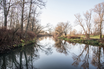 Fototapeta na wymiar autumn scenery with river and trees around reflected on waterground