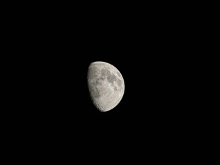 A half moon as seen against a clear black sky from the Northern Hemisphere in the UK.