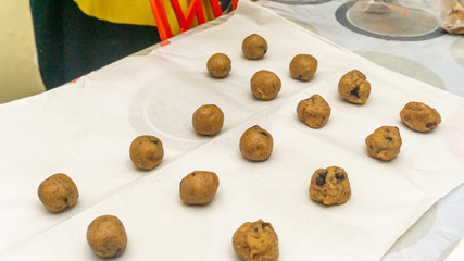 Close up view of raw cookies with chocolate chips before baking on a cover paper on a tray. Detail and texture view.
