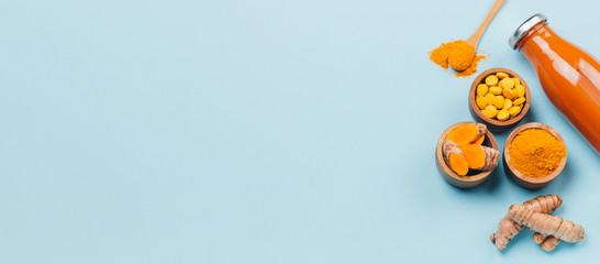 Fototapeta premium Turmeric in different states: fresh in bottle, pills, powder and cut plant on wooden tray, dry root in wooden bowl.