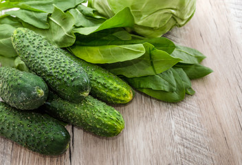 green vegetables on a wooden background. Cucumbers, cabbage and sorrel.
