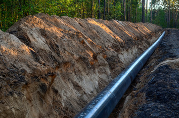 Natural gas pipeline construction work. A dug trench in the ground for the installation and...