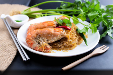 Casseroled prawns with vermicelli on white table or glass noodle bake with shrimp. Shrimp potted with vermicelli.