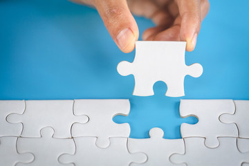 Hand put the last piece of jigsaw puzzle to complete the mission. Completing final task, missing...