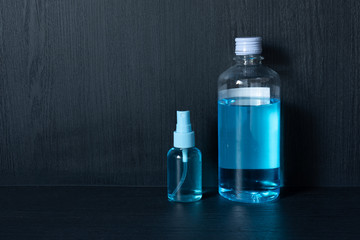 Blue alcohol hand sanitizer in clear spray bottle with black background, for killing germs, bacteria and viruses. Prevent the spread of germs and bacteria and avoid infections corona virus (COVID-19).