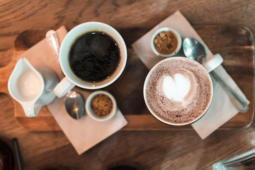 Top view of cup of coffee with milk froth heart shape on wooden table, Selective focus.