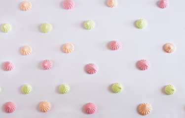many multi-colored meringues lie staggered on a light background
