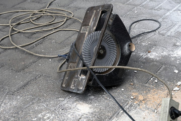 Hand-held circular saw near tangled electric wires, violation of safety rules while working with electric tools