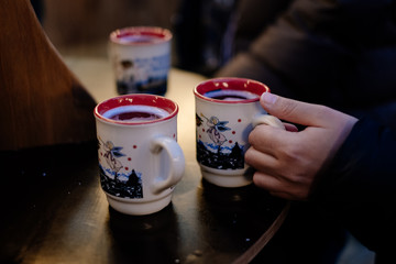 3 cups of steaming hot mulled wine on a table; Christmas market in winter