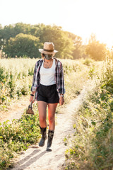 Young farmer woman walking with straw hat surgical mask and hoe