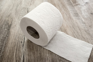 white toilet paper on a wooden background.