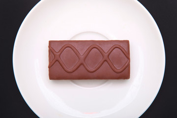 Chocolate biscuit in a white plate isolated on a black background