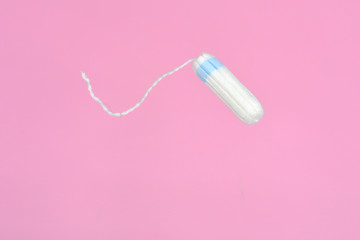 Medical female flyeng tampon on a pink background. Hygienic white tampon for women. Menstruation, means of protection.