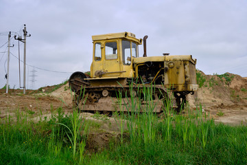 An old rusty, abandoned yellow bulldozer in a field.