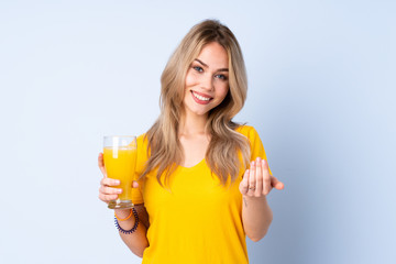 Teenager Russian girl holding an orange juice isolated on blue background inviting to come with hand. Happy that you came