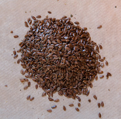 Pile of flax seeds on a light brown background. Top view