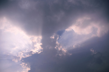 Beautiful white sun rays coming out from dark blue clouds