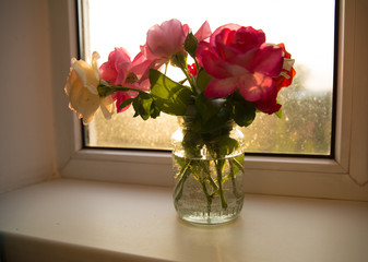 jar with roses on a windowsill