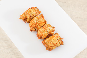 Chicken roll in grid decorated lettuce leaf isolated on wooden background. Fresh meat product whole and partly sliced. Chicken ham, and slices of tasty chicken meat. Natural product from organic farm.