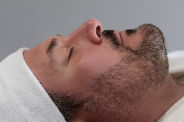 Obraz premium A side profile of a Caucasian man relaxing at a spa. He is ready to have a beauty skincare treatment and facial.