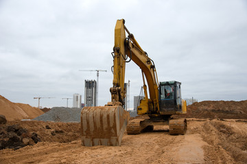 Excavators at earthworks on construction site. Backhoe loader digs a pit for the construction of...