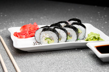 Rolls with vegetables on a white plate. Red Ginger Chinese sticks. Cup with soy sauce.