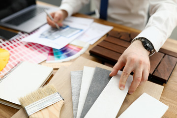 Male designer hand hold silver pen against color palette trend closeup background. Building...