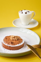 Tasty pastry cakes with nuts and a cup of coffee on a yellow background.