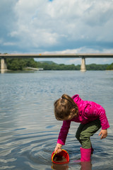 Balanced young girl kid playing on the natural river bank.