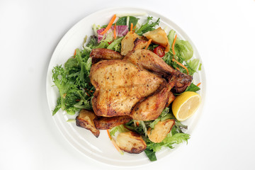 Whole roasted grilled chicken poultry bird with baked potato vegetable salad tomato lemon on white pate background
