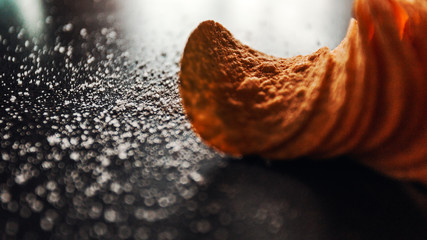 Crispy potato chips on a black table lie one after another, on which salt is scattered around the potato chips in macro focus, delicious yellow fresh chips pour a beer snack.