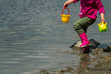 Balanced young girl kid playing on the natural river bank.