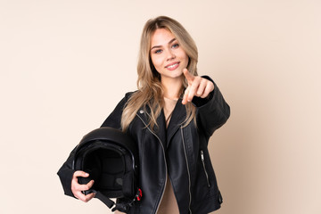 Russian girl with a motorcycle helmet isolated on beige background points finger at you with a confident expression