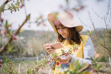 Pretty girl standing next to tree and looking at her phone