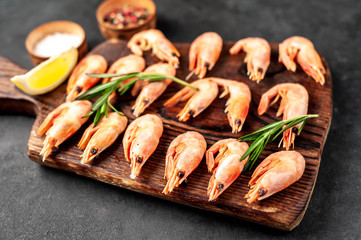 raw prawns on a chopping board
 blackboard with lemon and rosemary on a stone background