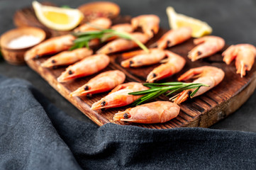 raw prawns in a white plate with lemon and rosemary on a stone background