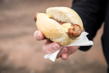 Mann isst unterwegs typisch deutsche Thüringer Rostbratwurst Bratwurst und Brötchen mit Senf